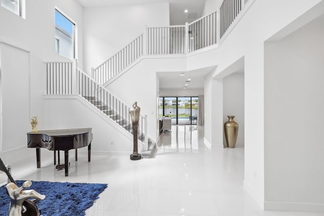 foyer featuring stairway, a high ceiling, baseboards, and recessed lighting