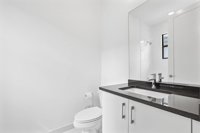 bathroom featuring toilet, baseboards, walk in shower, and vanity