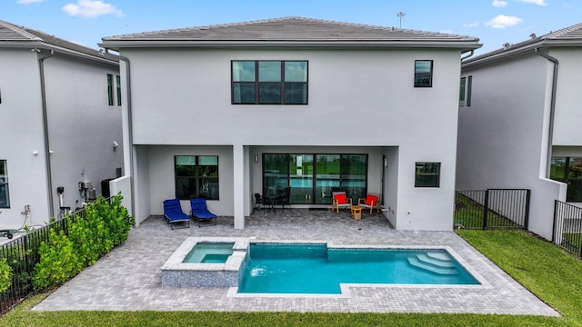 rear view of house featuring a pool with connected hot tub, a fenced backyard, a patio, and stucco siding