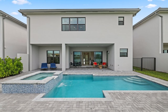 back of property with a pool with connected hot tub, stucco siding, a patio, and fence