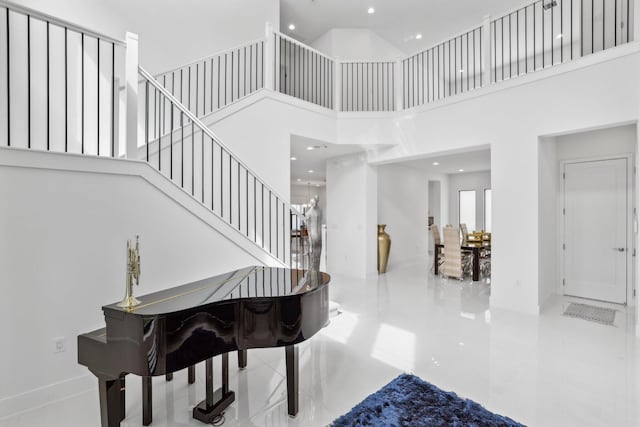 foyer featuring a towering ceiling, stairs, and recessed lighting