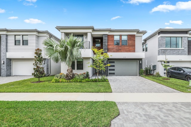 contemporary home with decorative driveway, an attached garage, and a front yard