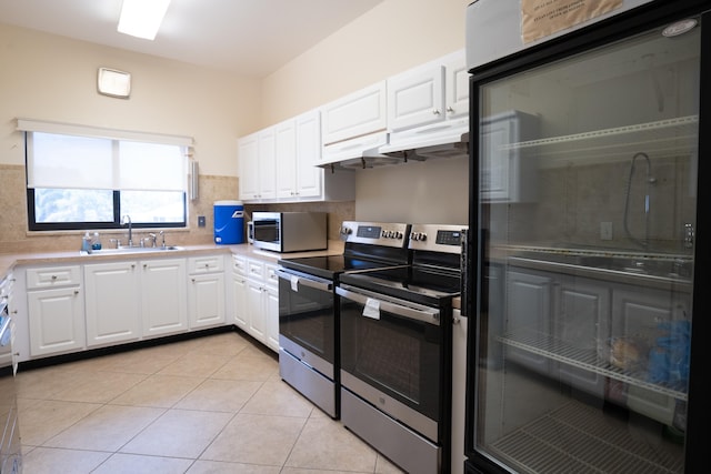 kitchen with appliances with stainless steel finishes, tasteful backsplash, sink, light tile patterned floors, and white cabinetry