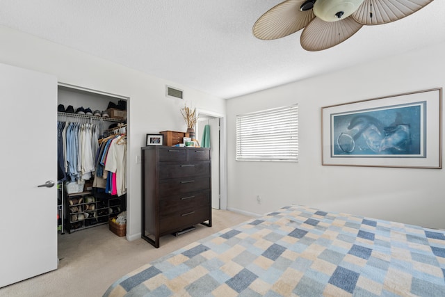 carpeted bedroom with a textured ceiling, a closet, and ceiling fan