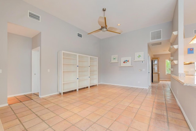 tiled empty room featuring a towering ceiling and ceiling fan