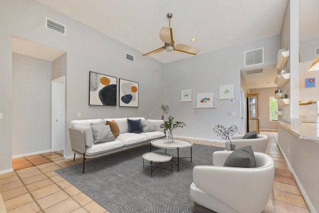 living room with ceiling fan, light tile patterned floors, and a high ceiling