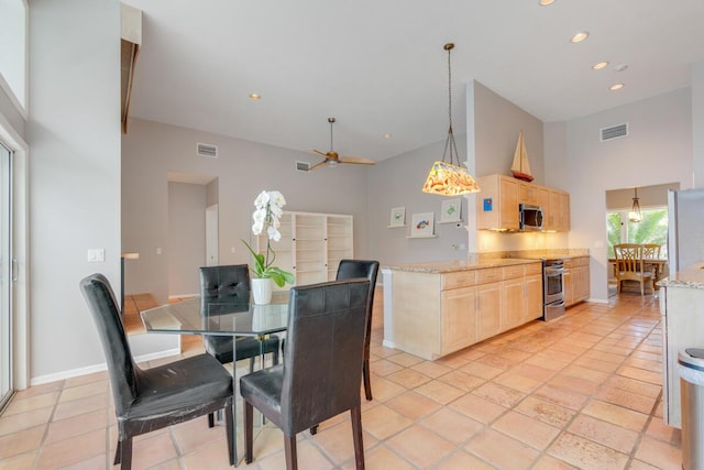 dining area featuring ceiling fan, a towering ceiling, and light tile patterned floors