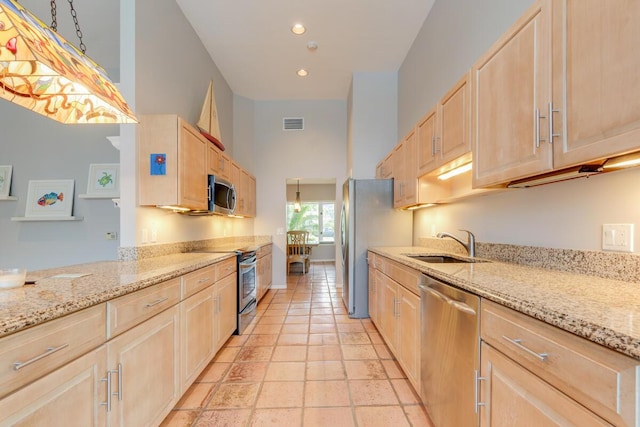 kitchen featuring light stone countertops, sink, light brown cabinets, light tile patterned floors, and appliances with stainless steel finishes