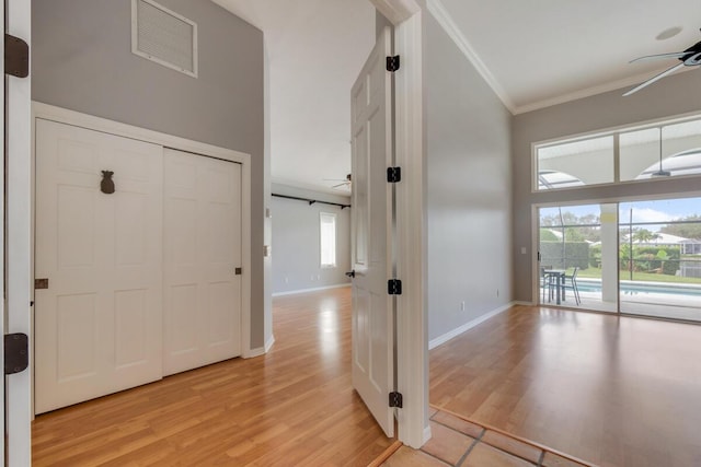 hall with plenty of natural light, light wood-type flooring, and ornamental molding