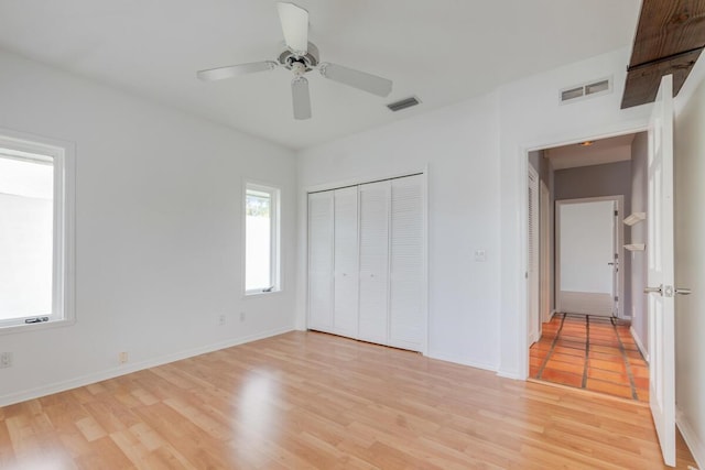 unfurnished bedroom featuring a closet, light hardwood / wood-style flooring, and ceiling fan