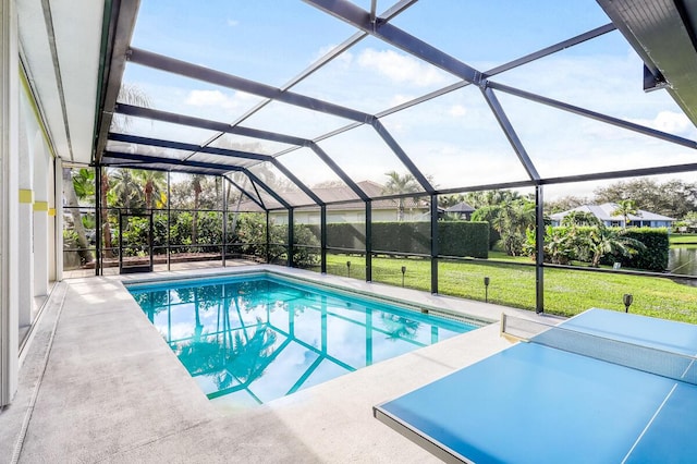 view of pool featuring a lawn, glass enclosure, and a patio