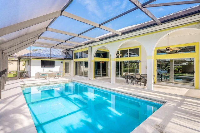 view of pool featuring a patio, glass enclosure, and ceiling fan