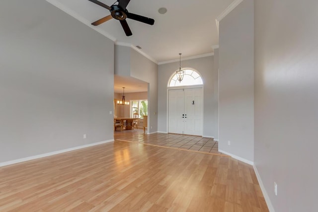 entrance foyer featuring light wood-type flooring, a towering ceiling, ceiling fan with notable chandelier, and crown molding