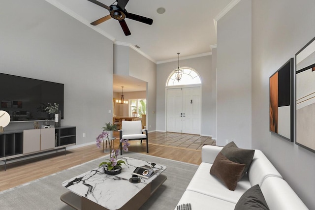 living room featuring wood-type flooring, ceiling fan with notable chandelier, and ornamental molding