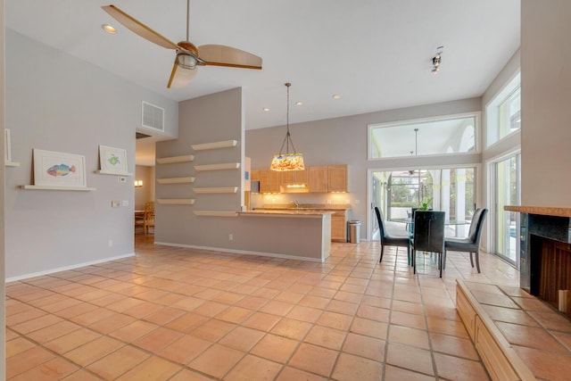 kitchen featuring a high ceiling, decorative light fixtures, light tile patterned floors, and ceiling fan