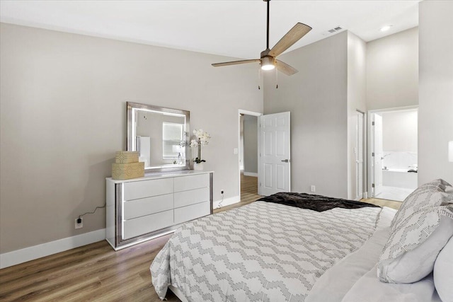 bedroom featuring ensuite bath, ceiling fan, light hardwood / wood-style floors, and a high ceiling