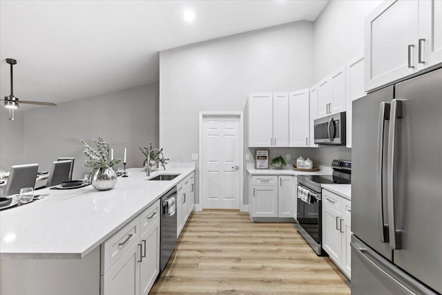 kitchen with appliances with stainless steel finishes, light wood-type flooring, white cabinetry, and sink