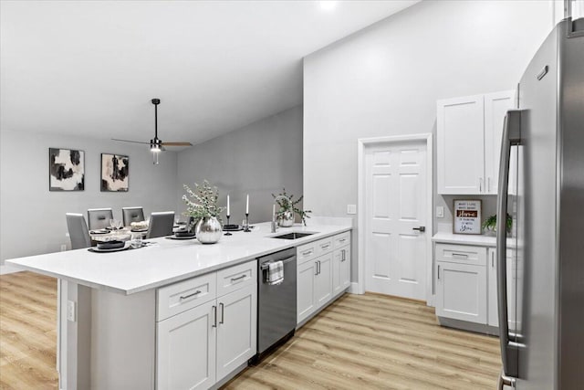 kitchen featuring kitchen peninsula, white cabinets, stainless steel appliances, and light hardwood / wood-style floors