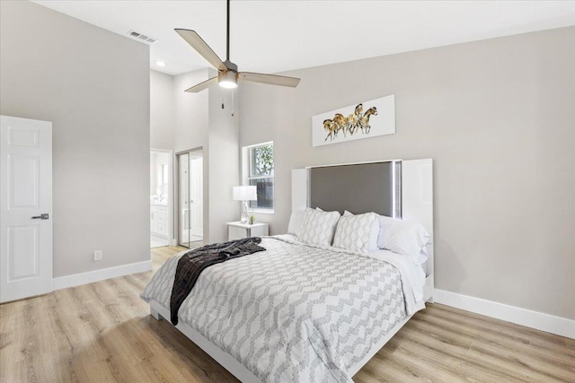 bedroom featuring ceiling fan, light hardwood / wood-style flooring, high vaulted ceiling, and ensuite bathroom