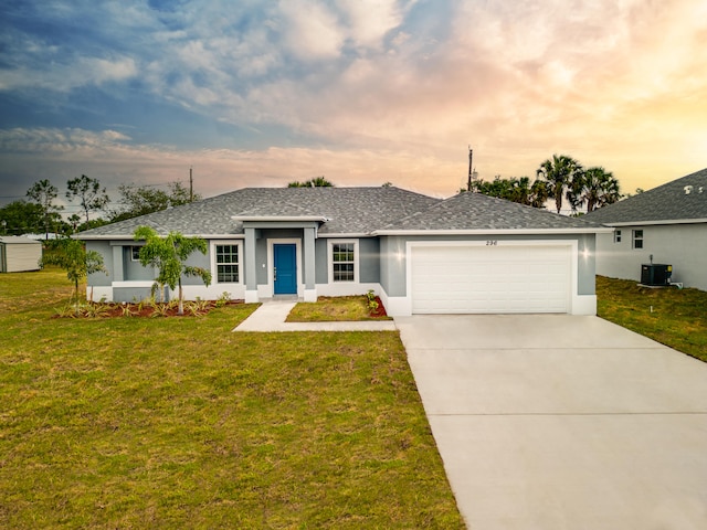 single story home with central air condition unit, a garage, and a yard