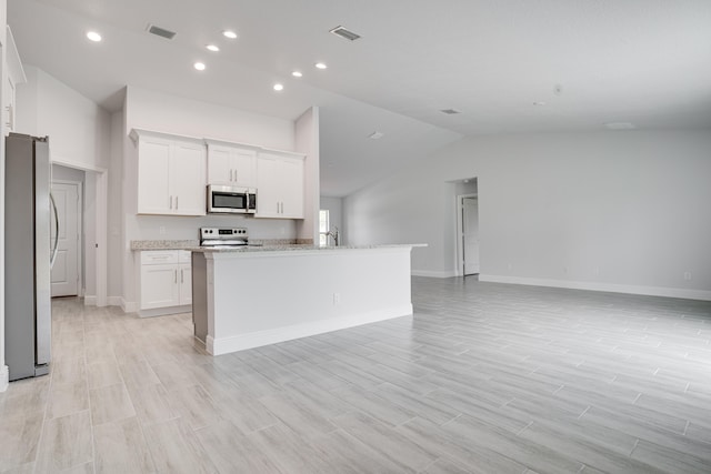 kitchen with appliances with stainless steel finishes, light stone countertops, vaulted ceiling, light hardwood / wood-style floors, and white cabinets