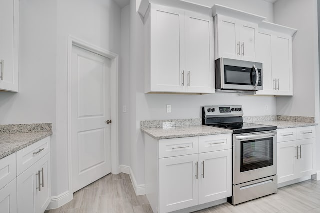 kitchen with white cabinetry, light stone counters, and appliances with stainless steel finishes