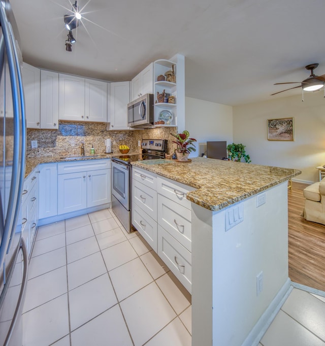 kitchen with light stone countertops, appliances with stainless steel finishes, white cabinetry, tasteful backsplash, and sink