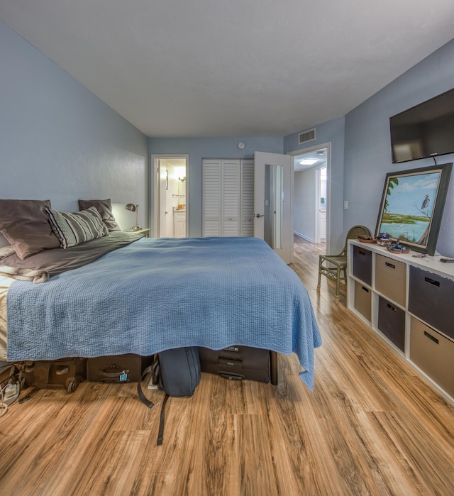 bedroom featuring light wood-type flooring and connected bathroom