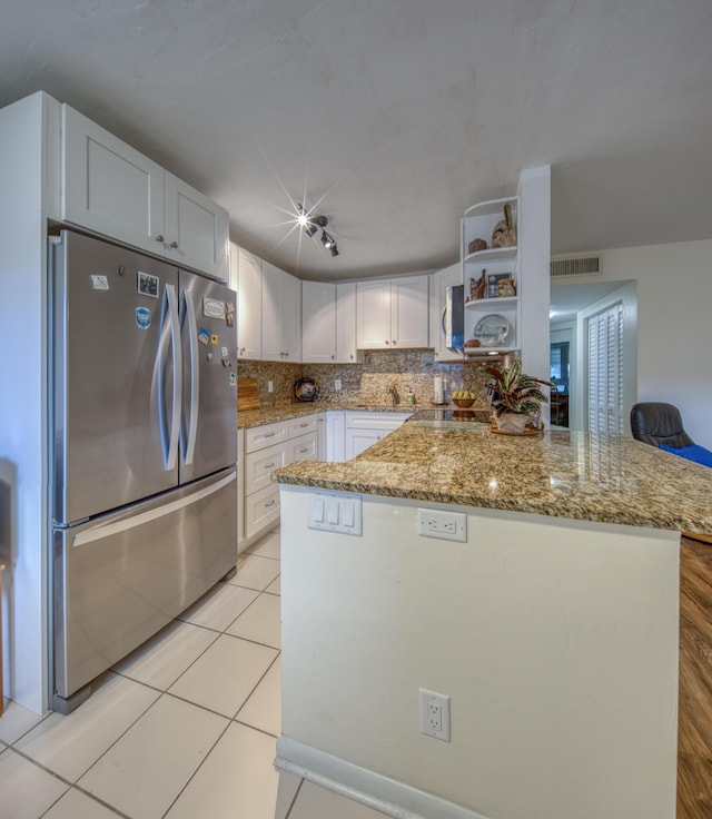 kitchen with tasteful backsplash, white cabinets, kitchen peninsula, and stainless steel refrigerator