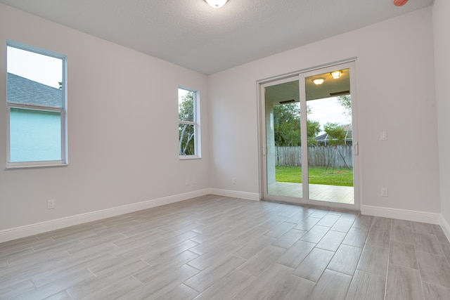 unfurnished room featuring a textured ceiling and light hardwood / wood-style flooring