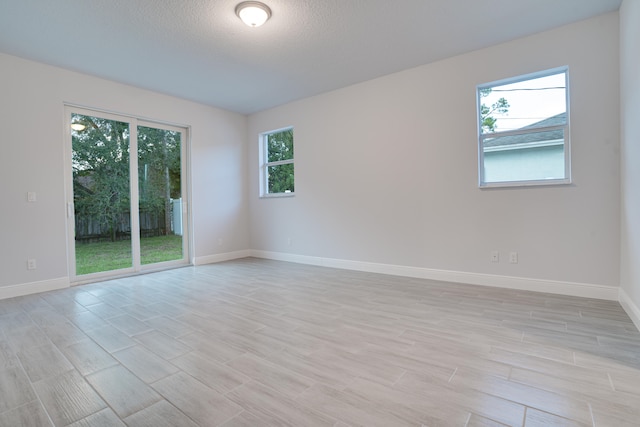 unfurnished room with light wood-type flooring and a textured ceiling