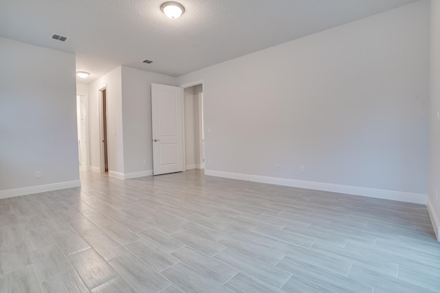 empty room featuring a textured ceiling and light wood-type flooring