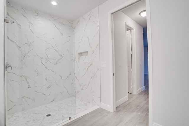 bathroom with wood-type flooring and tiled shower