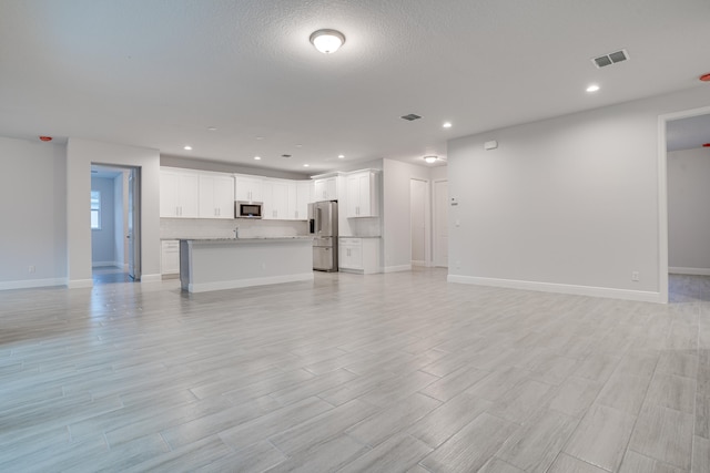 unfurnished living room featuring light hardwood / wood-style floors and a textured ceiling