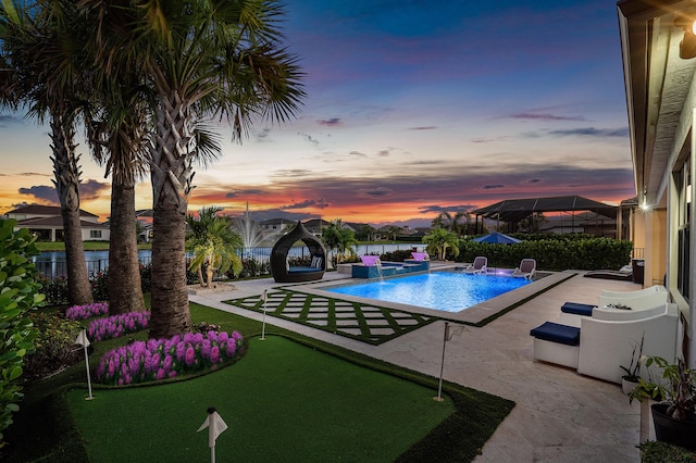 pool at dusk featuring pool water feature and a patio