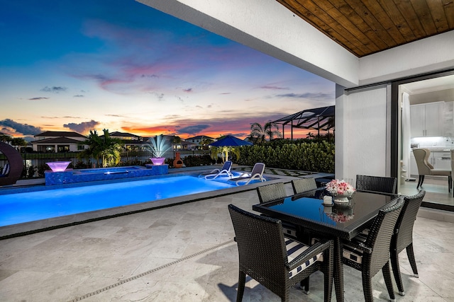 pool at dusk featuring a patio area and pool water feature