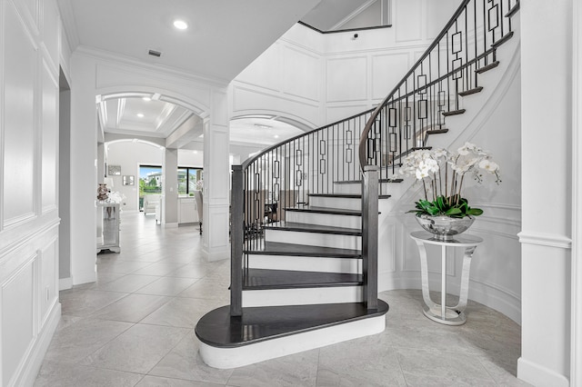 stairs with tile patterned floors, ornate columns, and crown molding