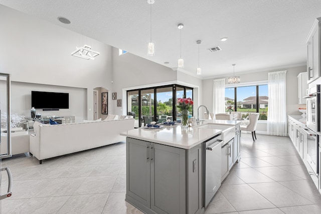 kitchen with stainless steel appliances, sink, pendant lighting, a center island with sink, and white cabinetry