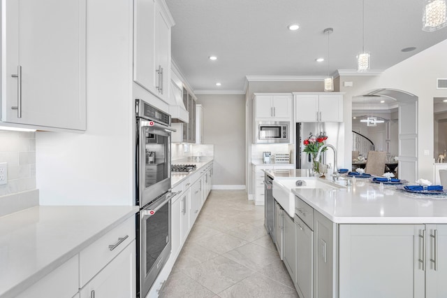 kitchen with pendant lighting, backsplash, sink, appliances with stainless steel finishes, and white cabinetry