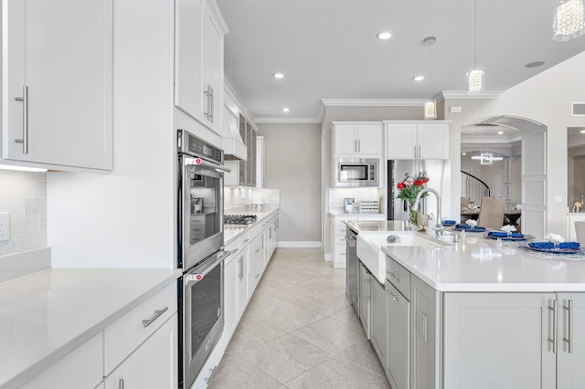 110 Echelon Crest Trl, Jupiter, FL 33478 - kitchen featuring crown molding, stainless steel appliances, decorative backsplash, light countertops, and arched walkways