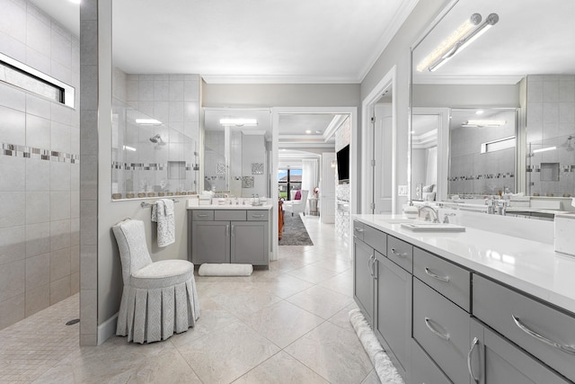 bathroom with tiled shower, vanity, ornamental molding, and tile patterned flooring