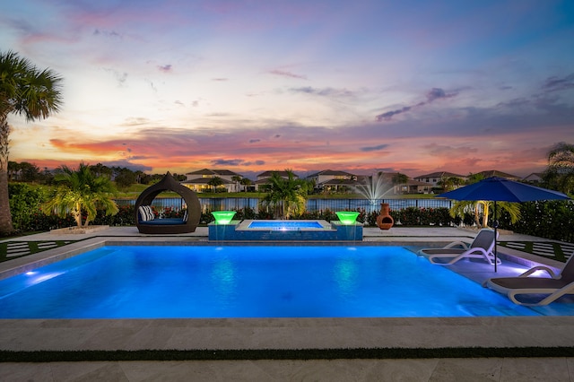 pool at dusk featuring an in ground hot tub