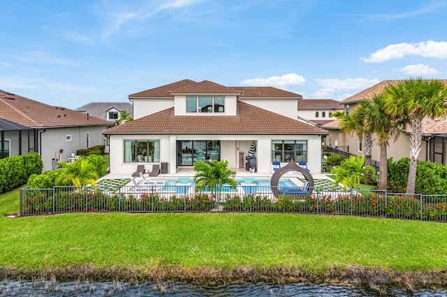 back of house with a yard, a fenced in pool, a patio, and a water view