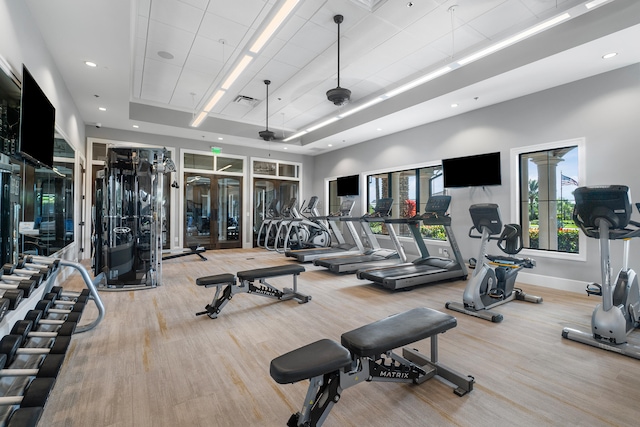 workout area featuring hardwood / wood-style flooring and a raised ceiling