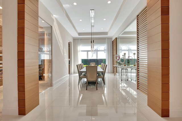 tiled dining area with a raised ceiling