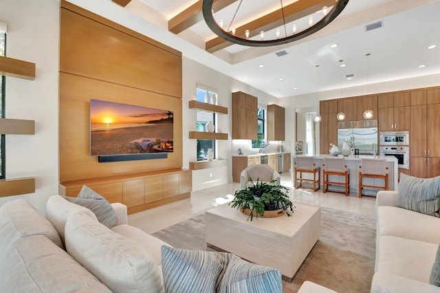 tiled living room featuring sink, an inviting chandelier, a towering ceiling, and beamed ceiling