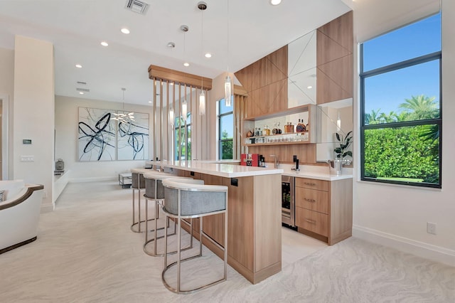 kitchen featuring decorative light fixtures, a kitchen island, wine cooler, and a kitchen bar