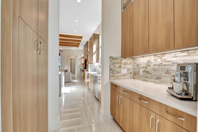 kitchen with dishwasher, light stone counters, light brown cabinets, light tile patterned floors, and backsplash