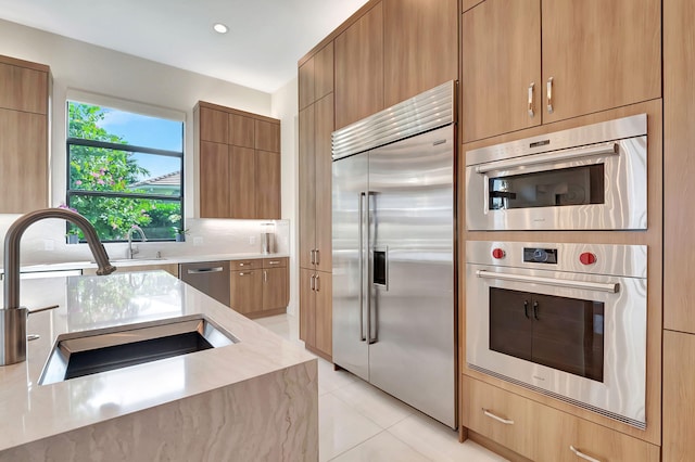 kitchen featuring appliances with stainless steel finishes, tasteful backsplash, light tile patterned flooring, and sink