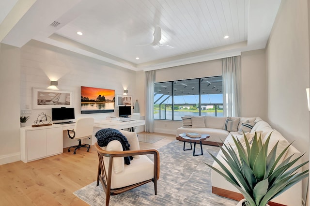 living room with built in desk, a raised ceiling, light wood-type flooring, ceiling fan, and wood ceiling